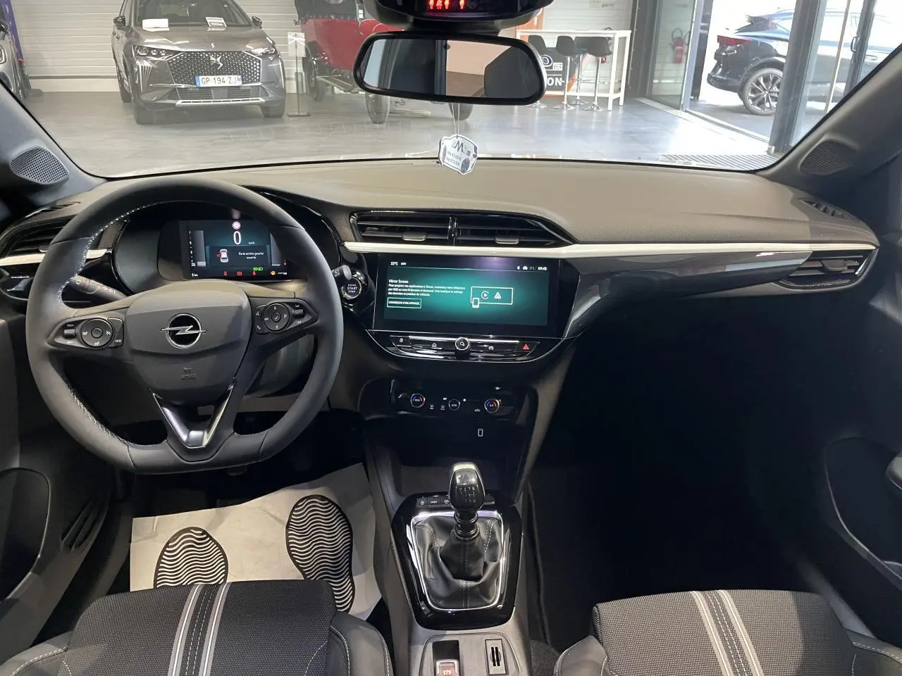 Intérieur avant de l'Opel Corsa blanc 2026, volant cuir, écran tactile 10 pouces et levier de vitesse manuel visible.