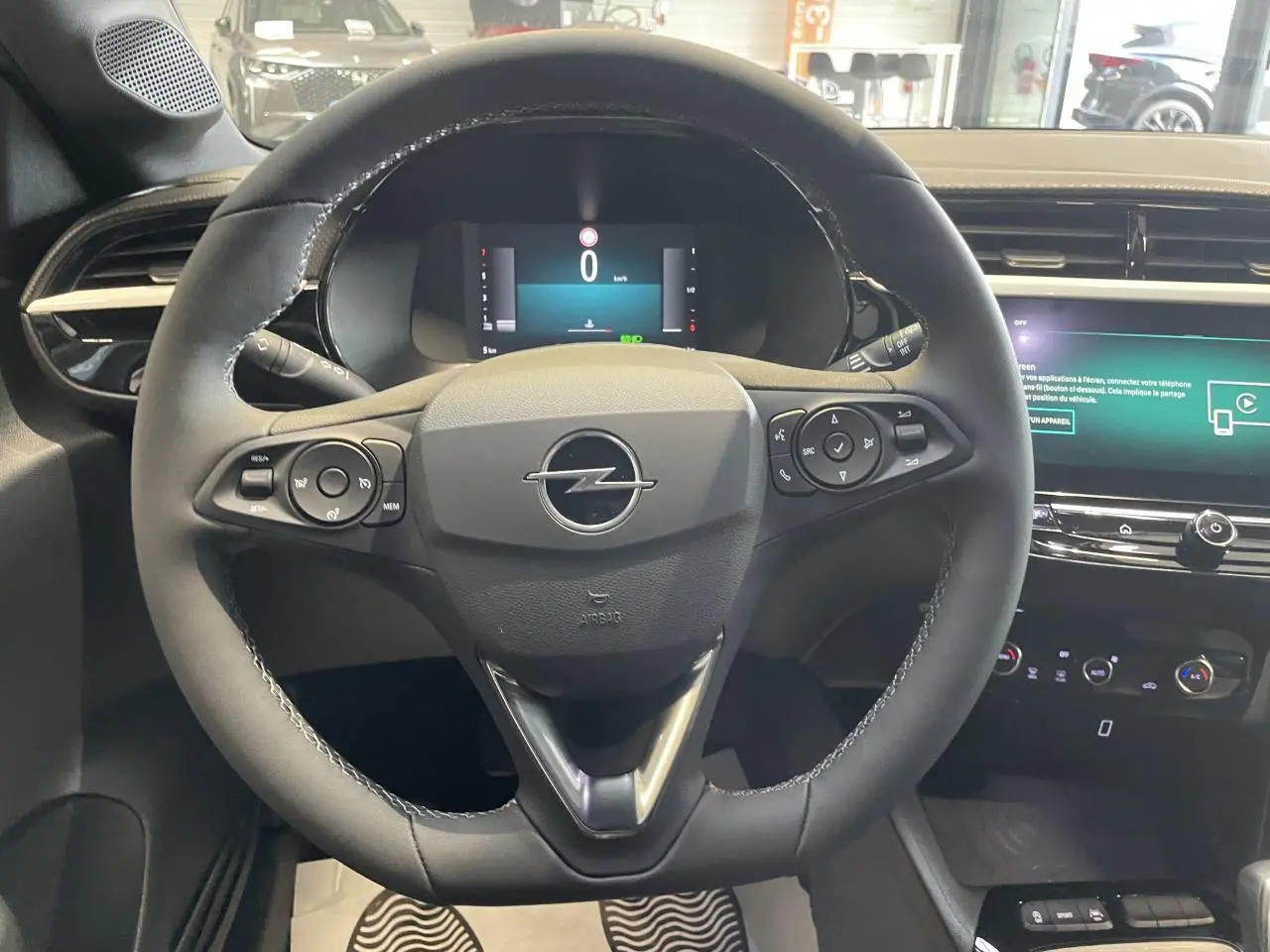 Vue intérieure centrée sur le volant noir de l'Opel Corsa 1.2 Turbo 2026 avec tableau de bord numérique et écran tactile.