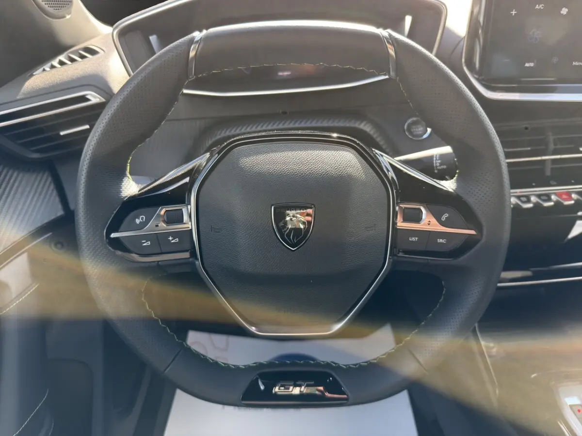 Volant cuir noir multifonctions de Peugeot 2008 Hybrid 145 e-DCS6 GT, vue frontale centrée sur le logo et commandes intégrées.