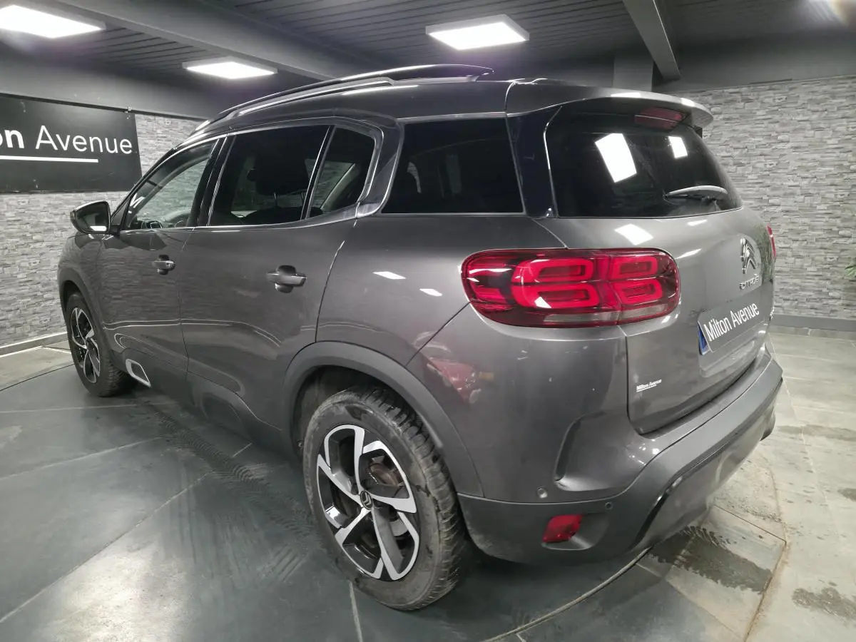 Vue 3/4 arrière droite d'un Citroën C5 Aircross gris métallisé avec jantes alliage et vitres teintées.