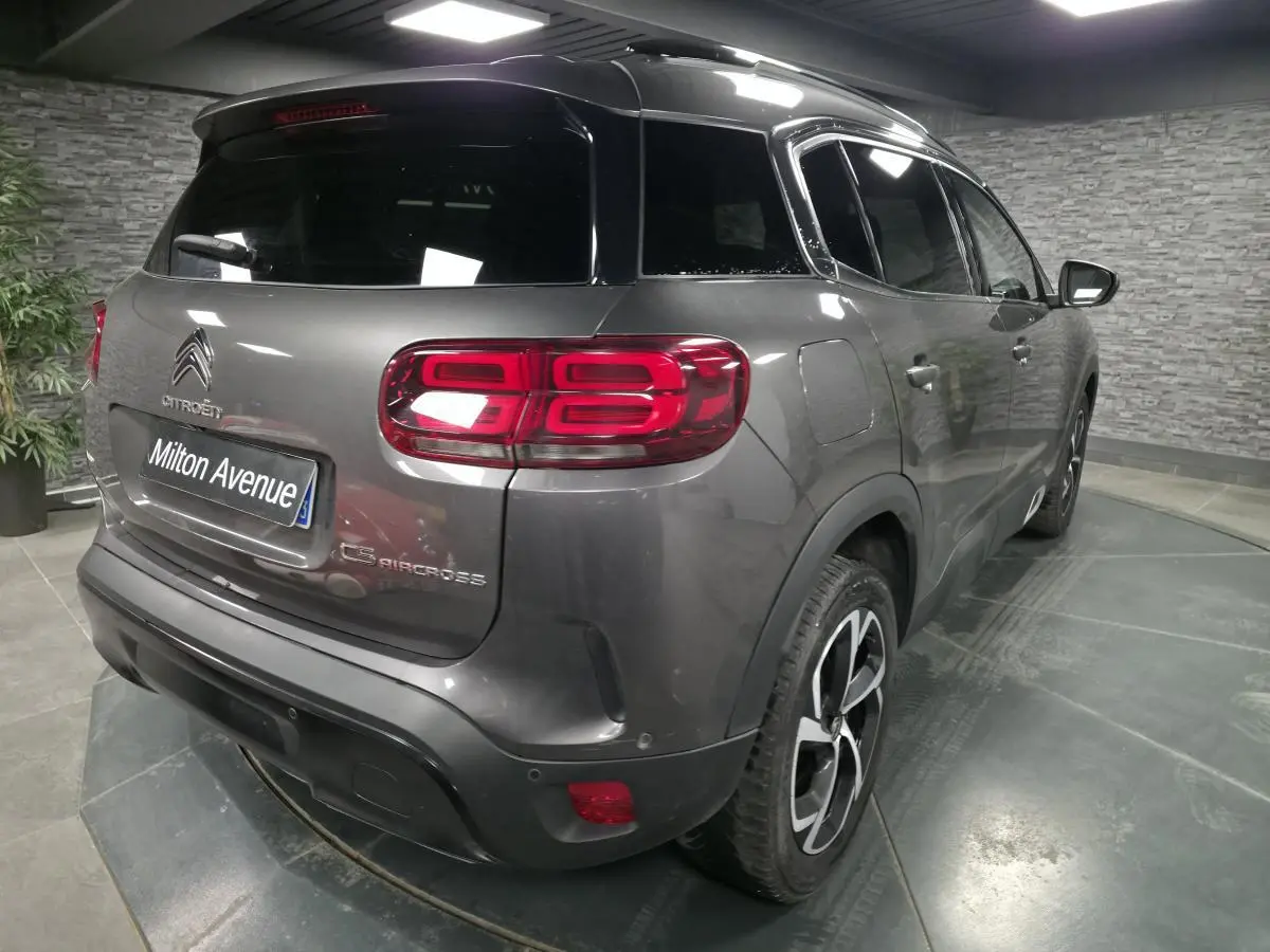 Vue 3/4 arrière droite d'un Citroën C5 Aircross gris métallisé avec feux arrière LED et jantes alliage noires.