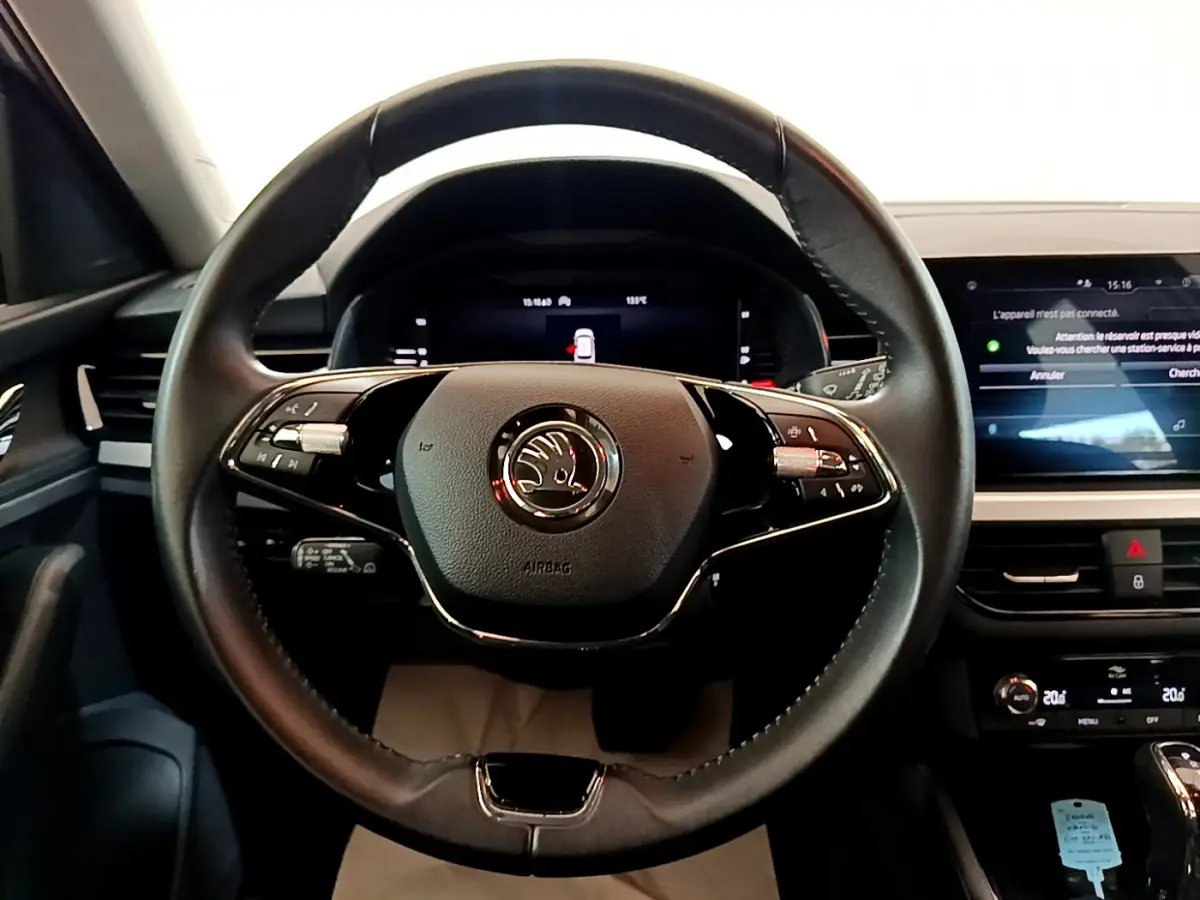 Volant cuir noir avec logo Skoda au centre, tableau de bord numérique et écran tactile dans l'habitacle du Kamiq gris clair.