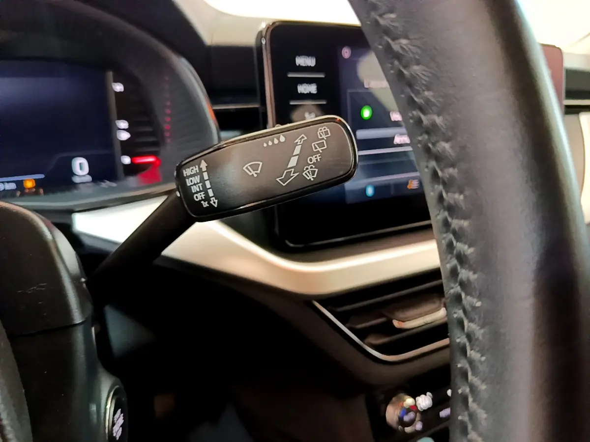 Gros plan sur la commande d’essuie-glace du tableau de bord noir et beige du Skoda Kamiq 2022, avec écran tactile en arrière-plan.