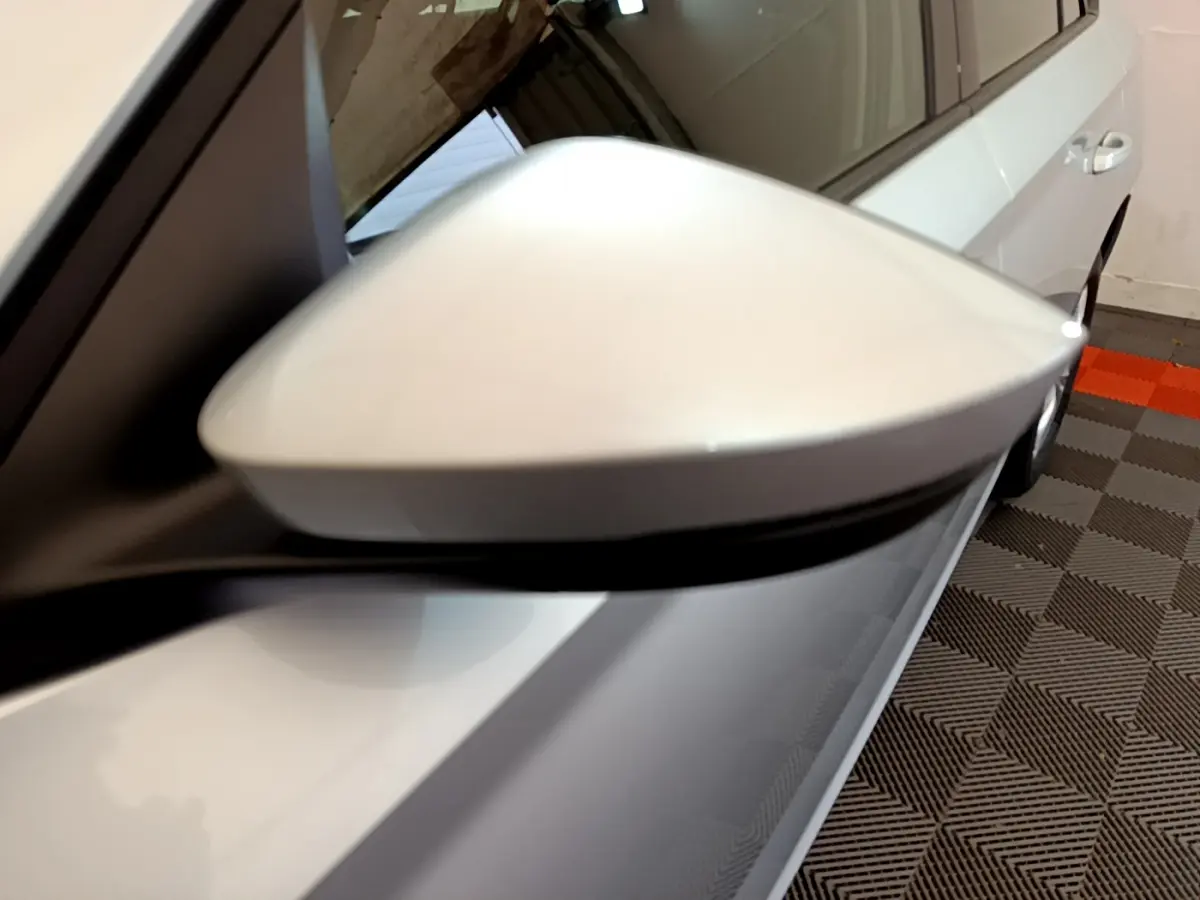 Gros plan sur le rétroviseur droit gris clair du Skoda Kamiq 2022, avec carrosserie et porte visibles en arrière-plan.
