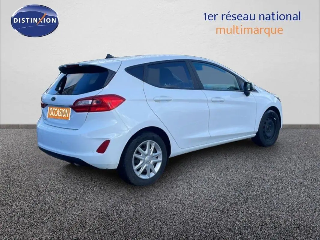 Vue 3/4 arrière droite d'une Ford Fiesta blanche avec vitres surteintées et jantes classiques 15 pouces.