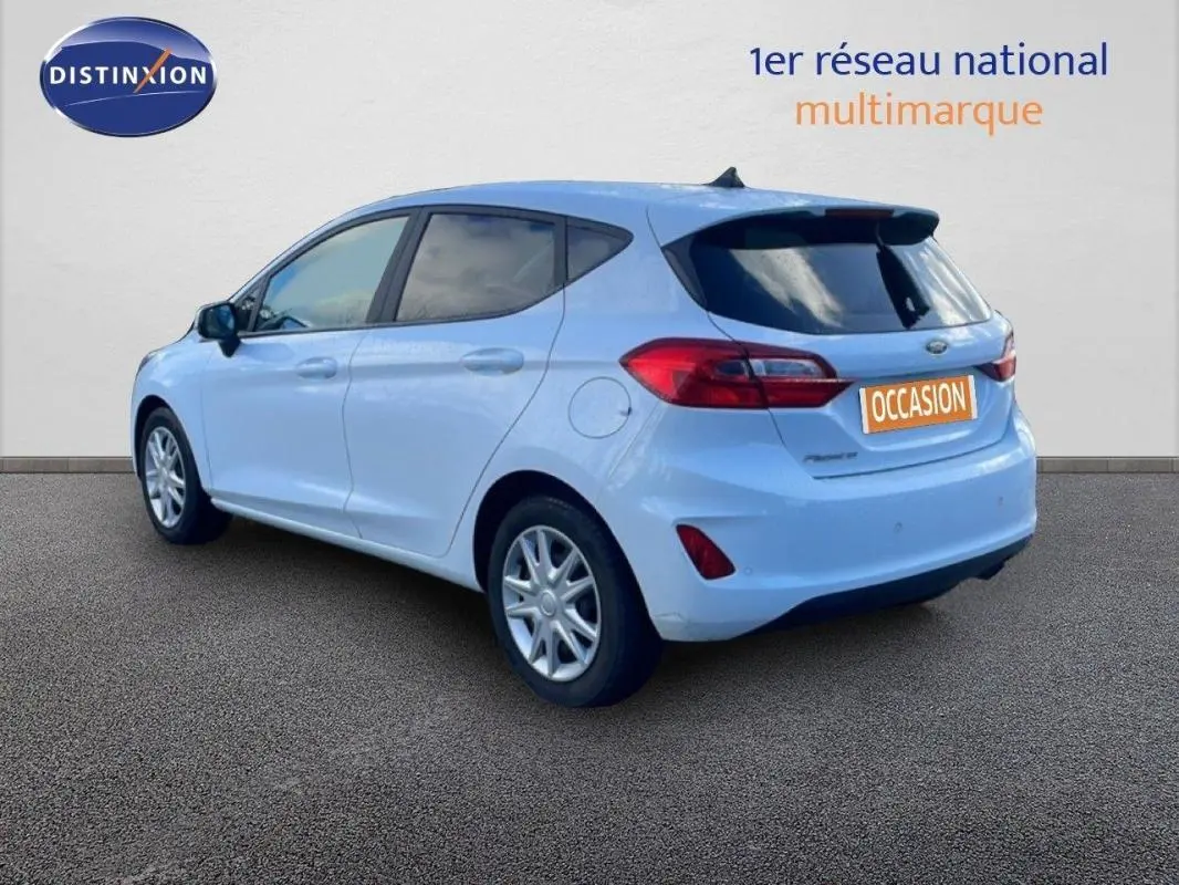 Vue 3/4 arrière droite d'une Ford Fiesta blanche avec vitres surteintées et jantes classiques 15 pouces.