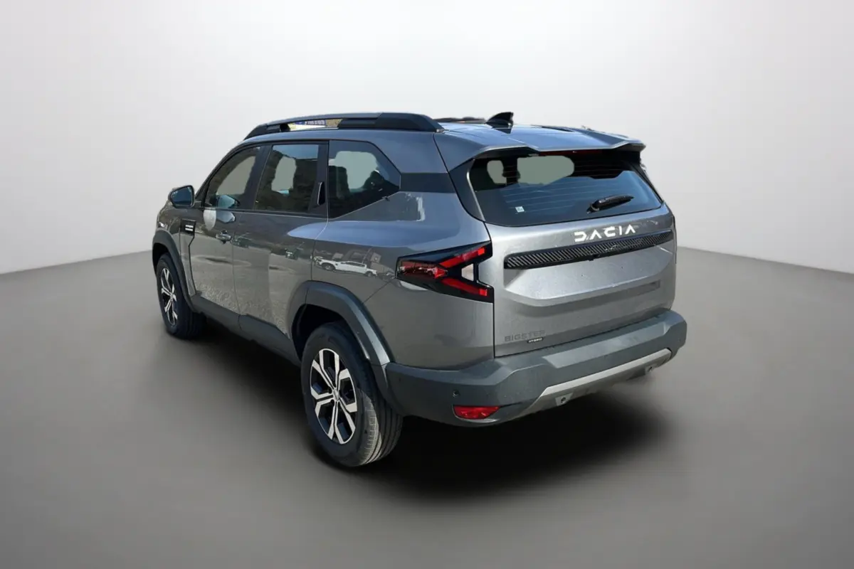 Vue 3/4 arrière droite du Dacia Bigster gris schiste avec barres de toit et jantes alu 17 pouces visibles.