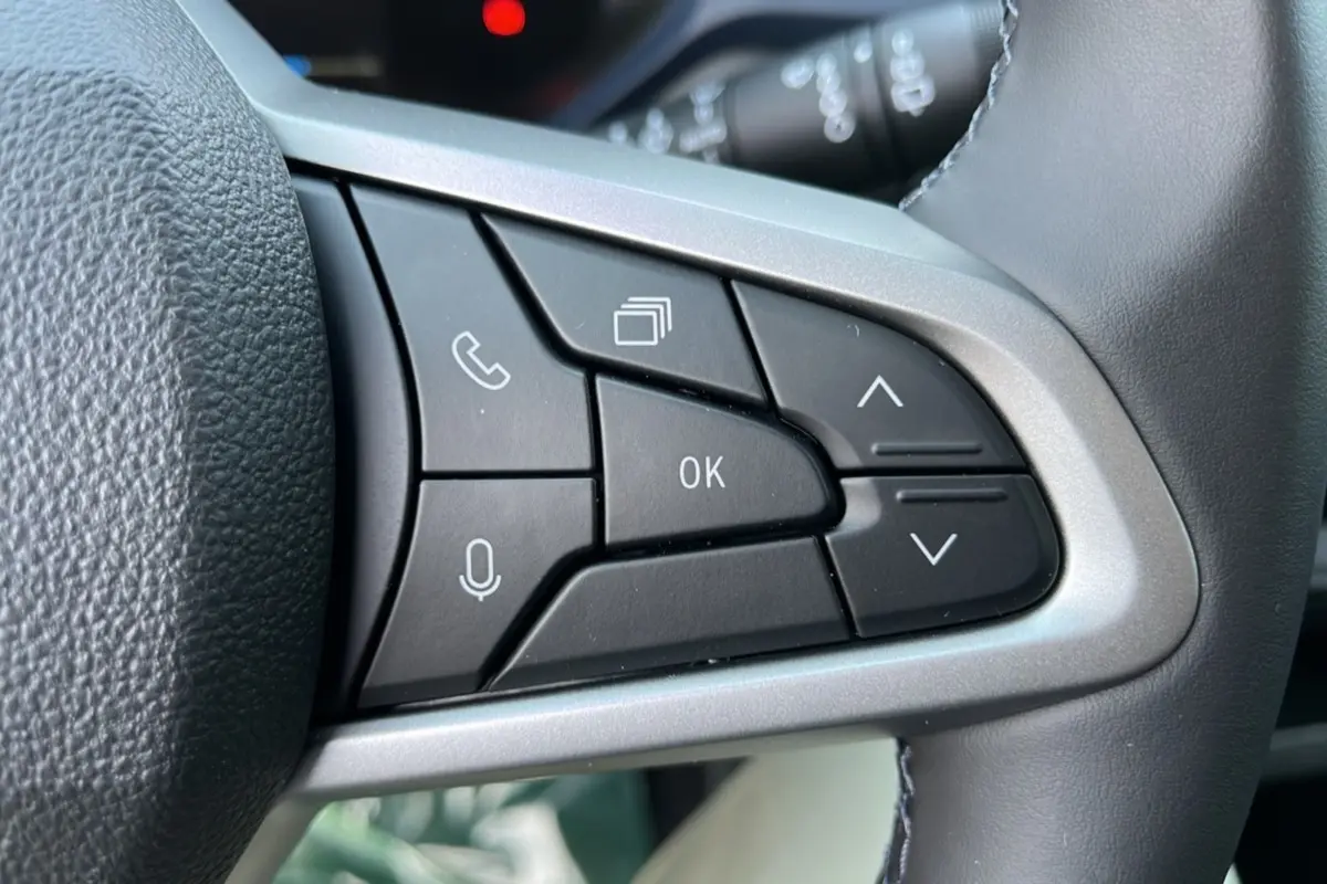 Gros plan sur les commandes multifonctions noires du volant cuir du Dacia Bigster Hybrid 155 Expression Plus.