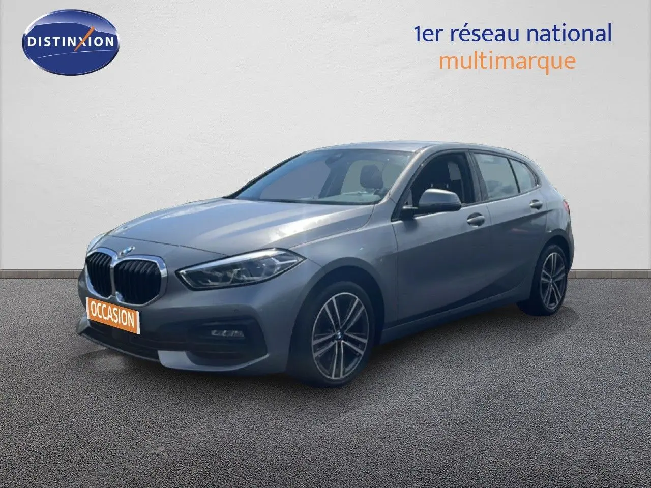 BMW Série 1 116i 2022 gris Frozen Pure Grey en 3/4 avant droit avec jantes bi-ton et calandre noire.
