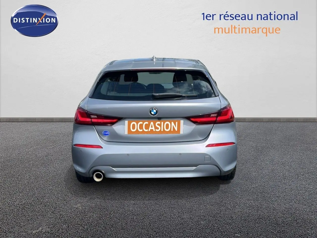 Vue arrière d'une BMW Série 1 116i gris mat Frozen Pure Grey avec feu arrière LED et sortie d'échappement côté gauche.