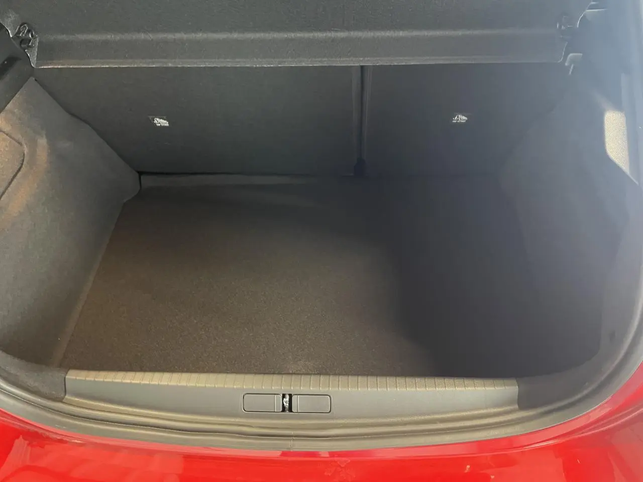 Coffre ouvert vu de face d’une Opel Corsa rouge 2026, montrant l’espace de chargement vide et bordure de coffre.