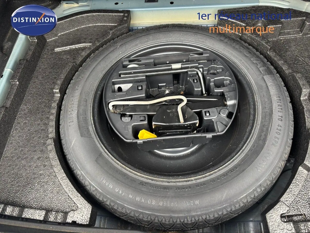 Roue de secours et outils de bord dans le coffre d'une Peugeot 308 Bleu Magnetic, vue en plongée rapprochée.