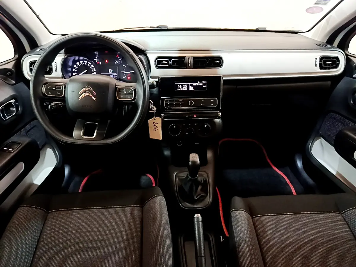 Vue intérieure avant de la Citroën C3 blanche 2018, tableau de bord moderne avec volant multifonction et boîte manuelle.