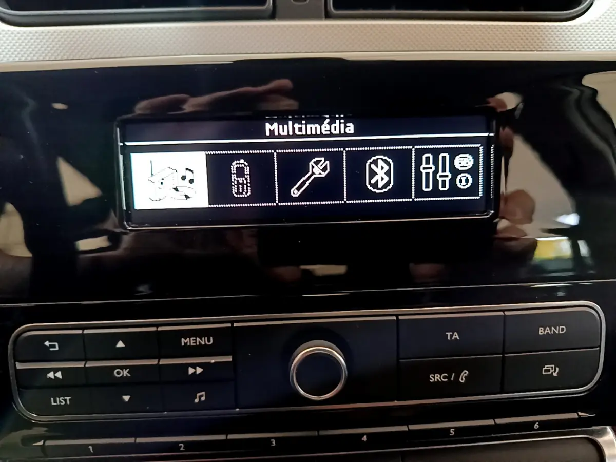 Gros plan sur l’écran multimédia et la console centrale noire du tableau de bord de la Citroën C3 blanche.