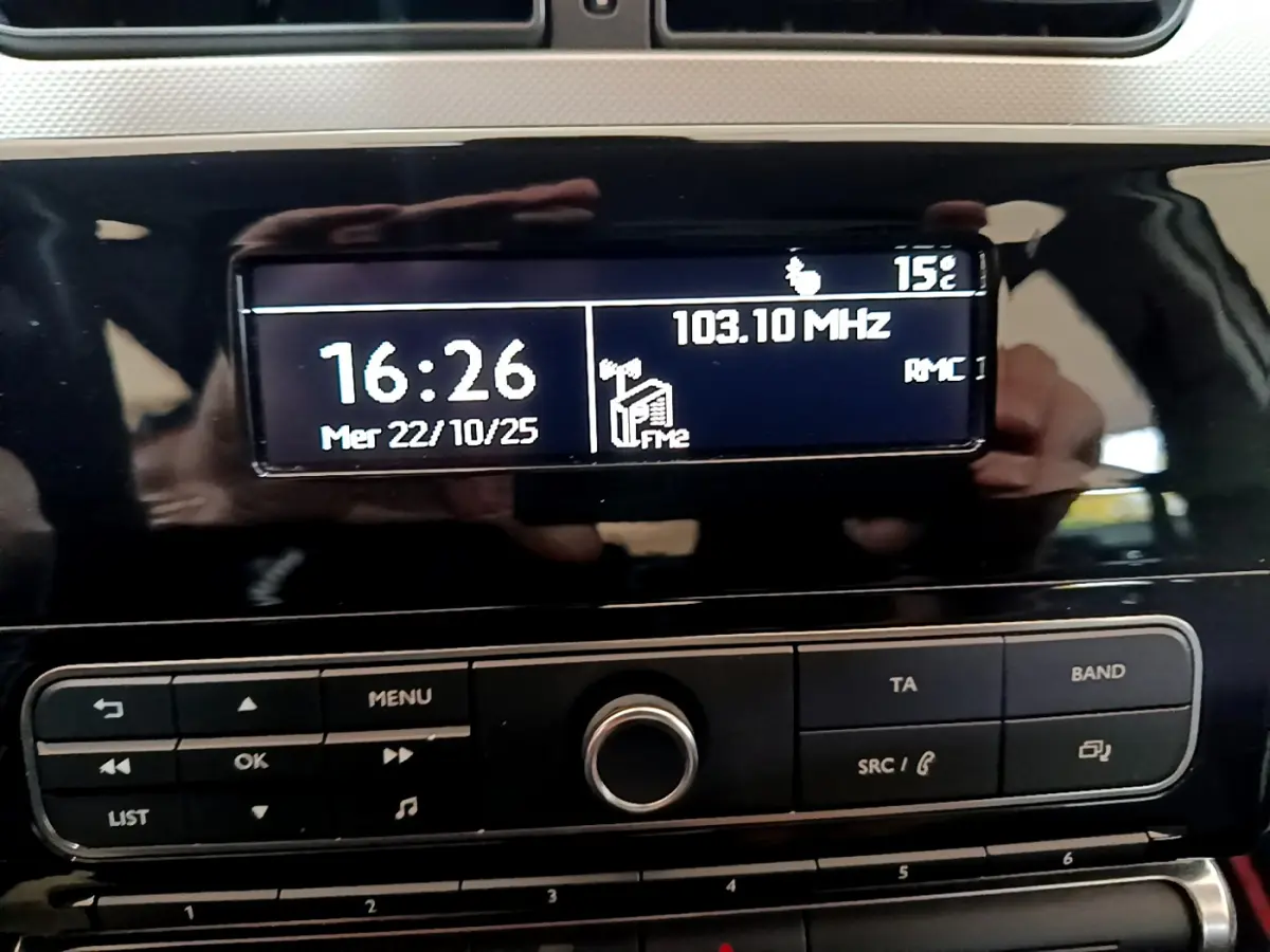 Affichage central de la radio et horloge sur tableau de bord noir brillant d'une Citroën C3 blanche de 2018.