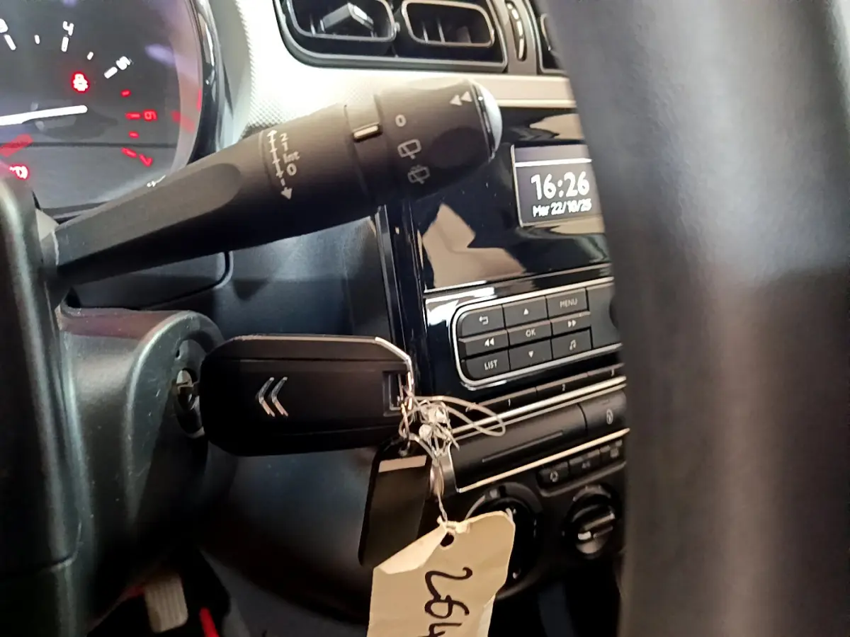 Vue rapprochée de l’intérieur d’une Citroën C3 blanche 2018, montrant la clé dans le contact et le tableau de bord noir.