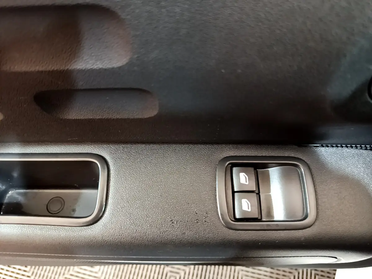 Gros plan sur les commandes des vitres électriques côté conducteur d'une Citroën C3 blanche, version PureTech 68 BVM Live.
