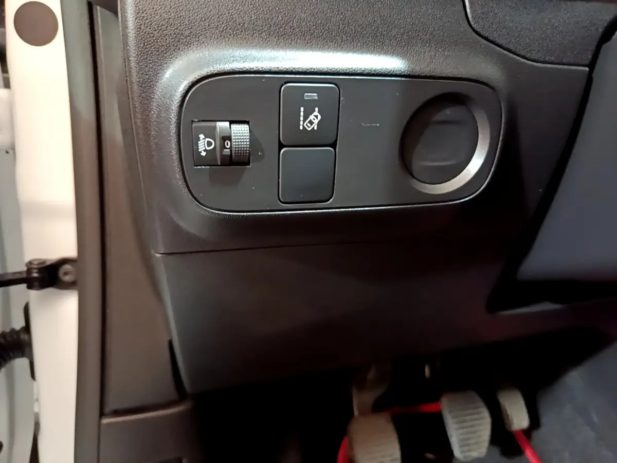 Vue rapprochée côté gauche du tableau de bord noir de la Citroën C3 blanche, avec commandes de réglage des phares et assistance.