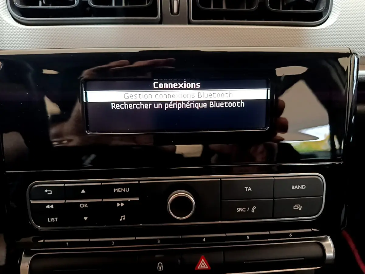 Gros plan sur l’écran central noir brillant de la Citroën C3 blanc, affichant le menu Bluetooth et les commandes audio.
