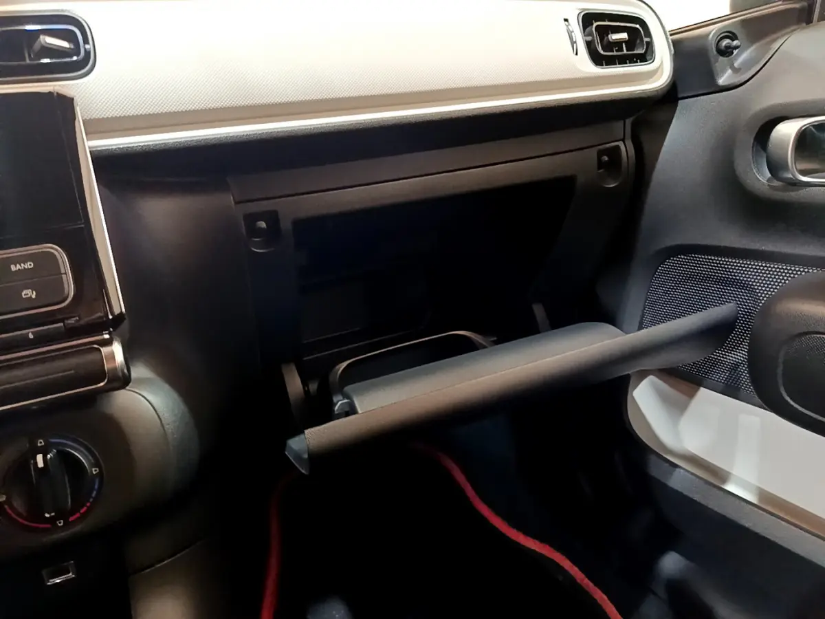 Intérieur de la Citroën C3 blanc 2018, vue côté passager avec boîte à gants ouverte et tableau de bord clair.