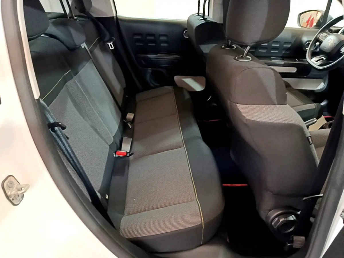 Vue intérieure côté arrière gauche du Citroën C3 blanc, montrant la banquette arrière et le siège avant côté conducteur.