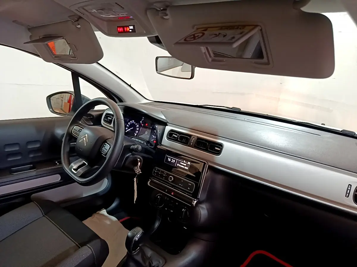 Vue intérieure côté conducteur du tableau de bord noir et gris de la Citroën C3 blanche avec volant multifonction et levier de vitesse manuel.