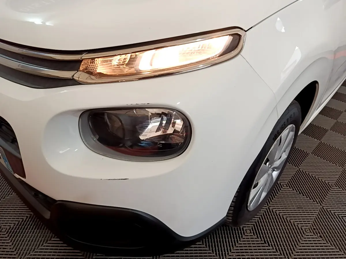 Gros plan sur l'avant droit blanc d'une Citroën C3 2018 avec phare allumé et jante visible.