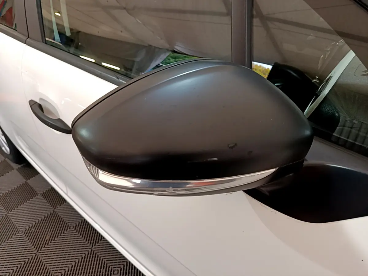 Gros plan sur le rétroviseur noir côté gauche d'une Citroën C3 blanche, avec clignotant intégré visible.