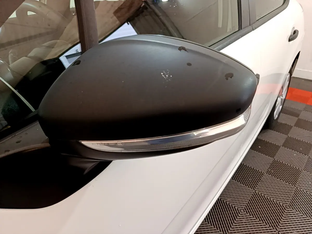 Gros plan sur le rétroviseur noir côté conducteur d'une Citroën C3 blanche vue de profil gauche.