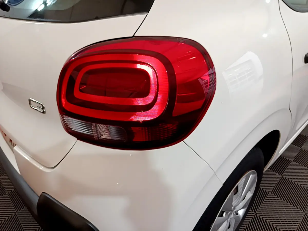 Gros plan sur le feu arrière droit rouge d'une Citroën C3 blanche, avec logo C3 visible sur la carrosserie.
