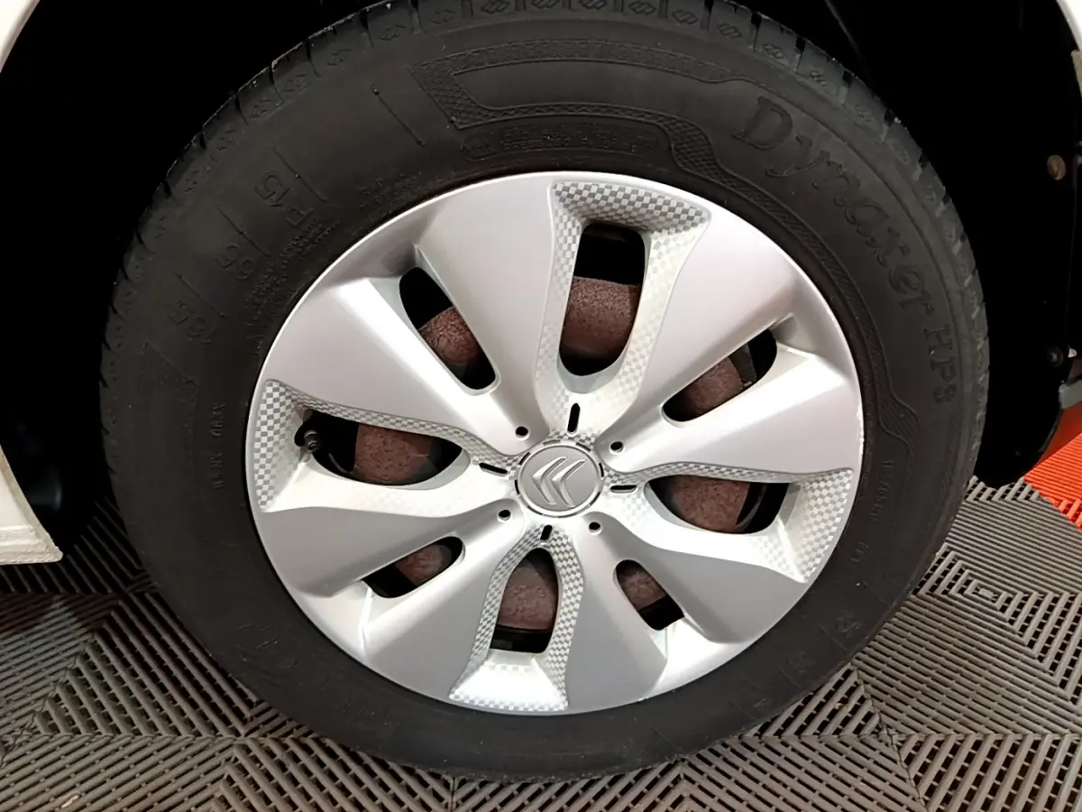 Gros plan sur la roue avant droite d'une Citroën C3 blanche de 2018 avec enjoliveur argenté au design moderne.