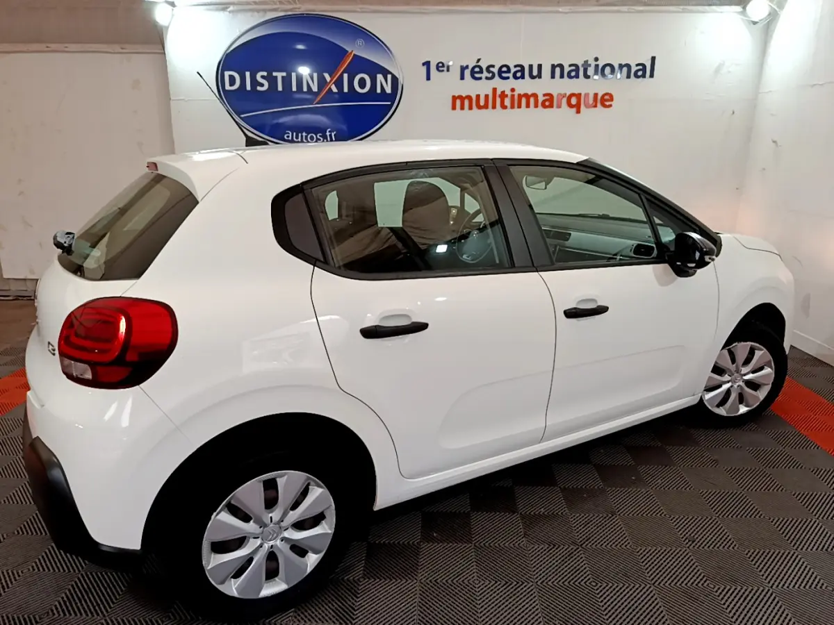 Citroën C3 blanche vue de profil droit en intérieur, avec poignées et rétroviseurs noirs contrastants.