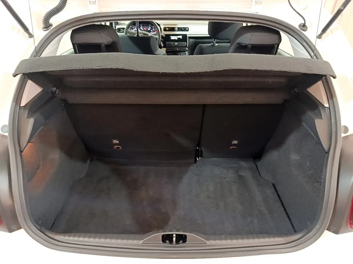 Coffre ouvert vu de l'arrière d'une Citroën C3 blanche, montrant l'espace de chargement et l'intérieur noir.
