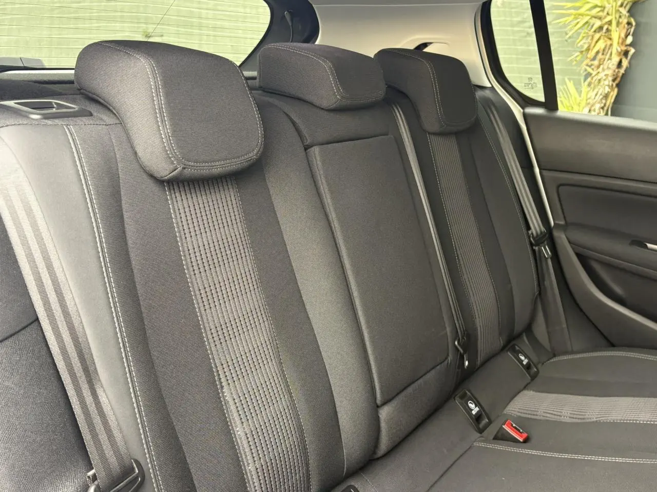 Vue intérieure des sièges arrière noirs de la Peugeot 308 1.2 PureTech 130 Allure avec appuie-têtes et ceintures visibles.