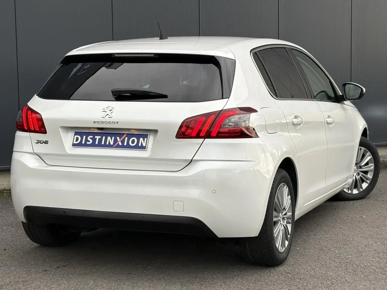 Vue 3/4 arrière droite d'une Peugeot 308 blanc nacré avec feux arrière LED et vitres surteintées