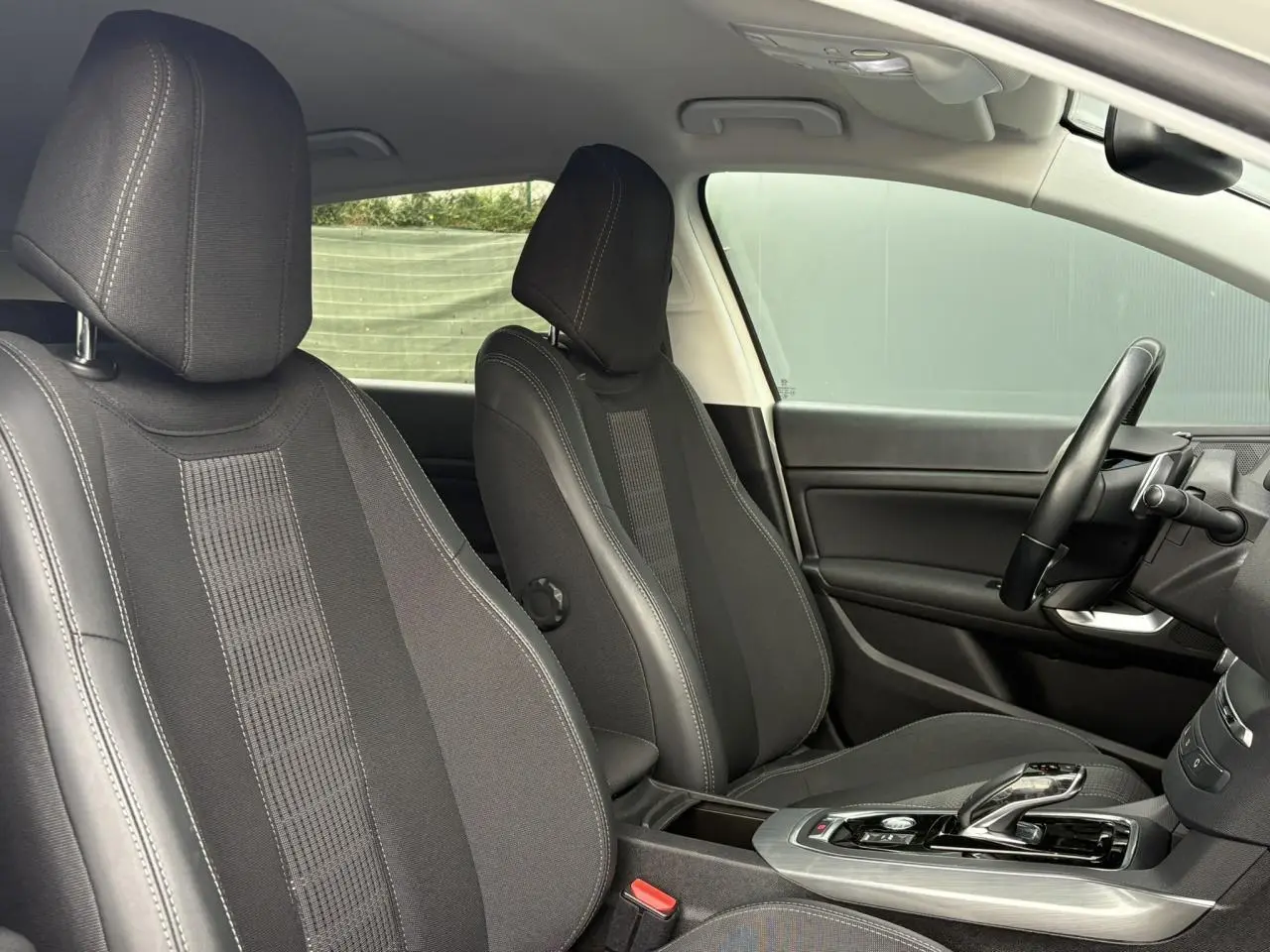 Vue intérieure côté conducteur de la Peugeot 308 2019 avec sièges noirs, volant cuir et console centrale moderne.