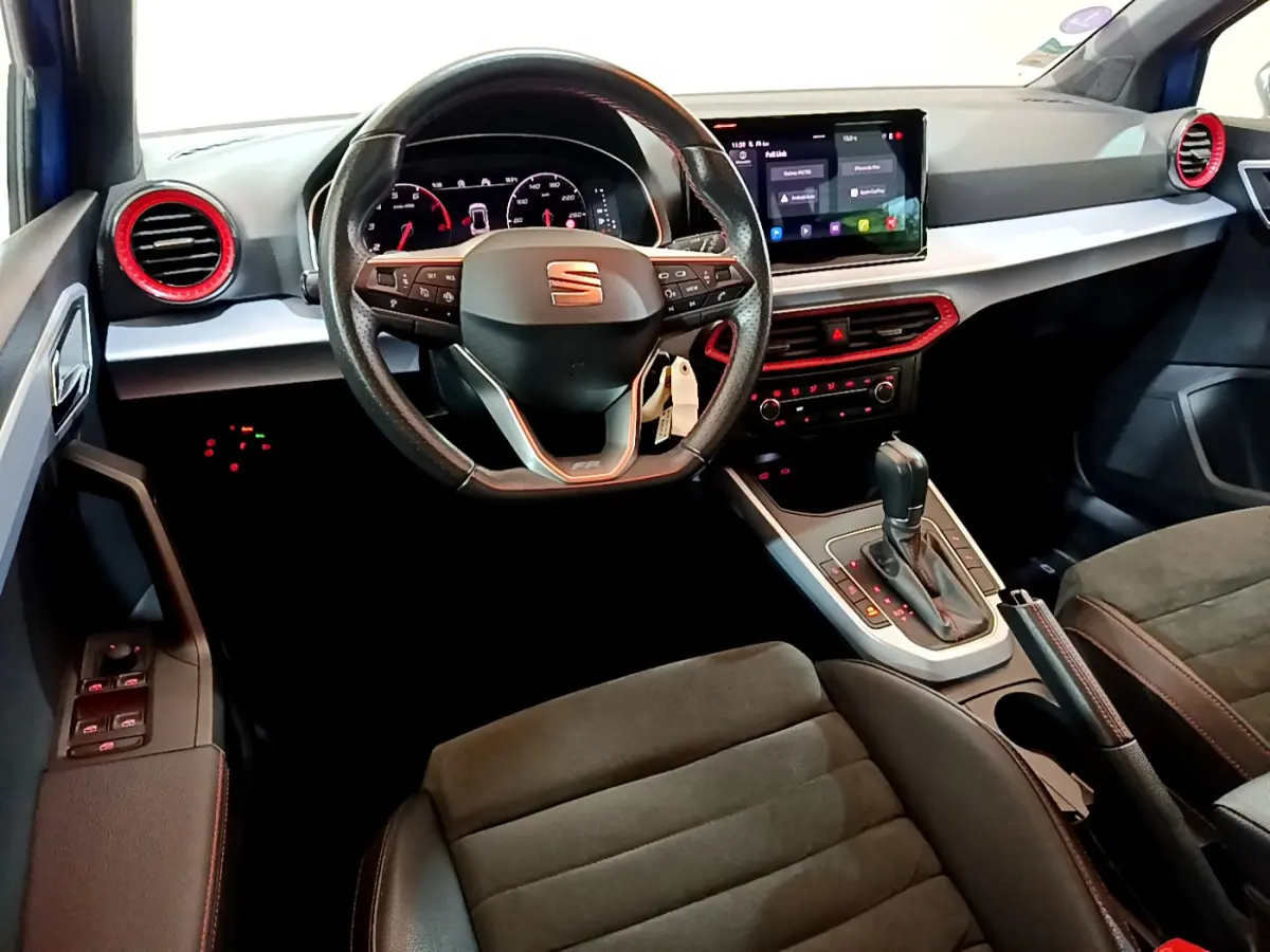Intérieur du SEAT Arona bleu, vue depuis le siège conducteur sur le volant, tableau de bord et écran tactile central.
