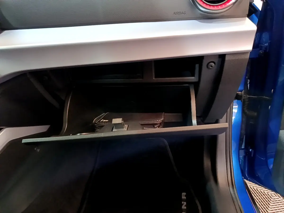 Gant de boîte à gants ouvert côté passager d'un SEAT Arona bleu 2022, montrant l'intérieur et une pochette noire.