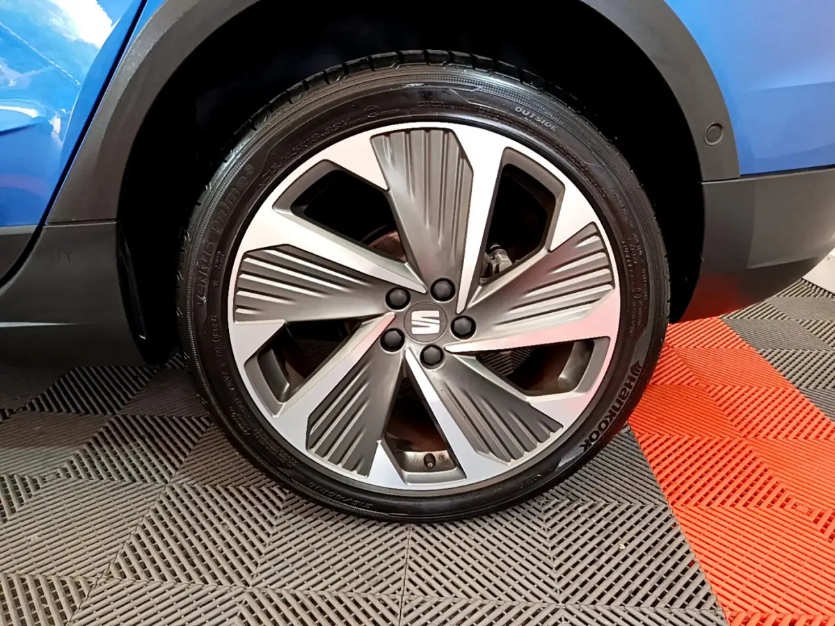 Gros plan sur la roue avant droite du SEAT Arona bleu 2022 avec jante alliage au design moderne.