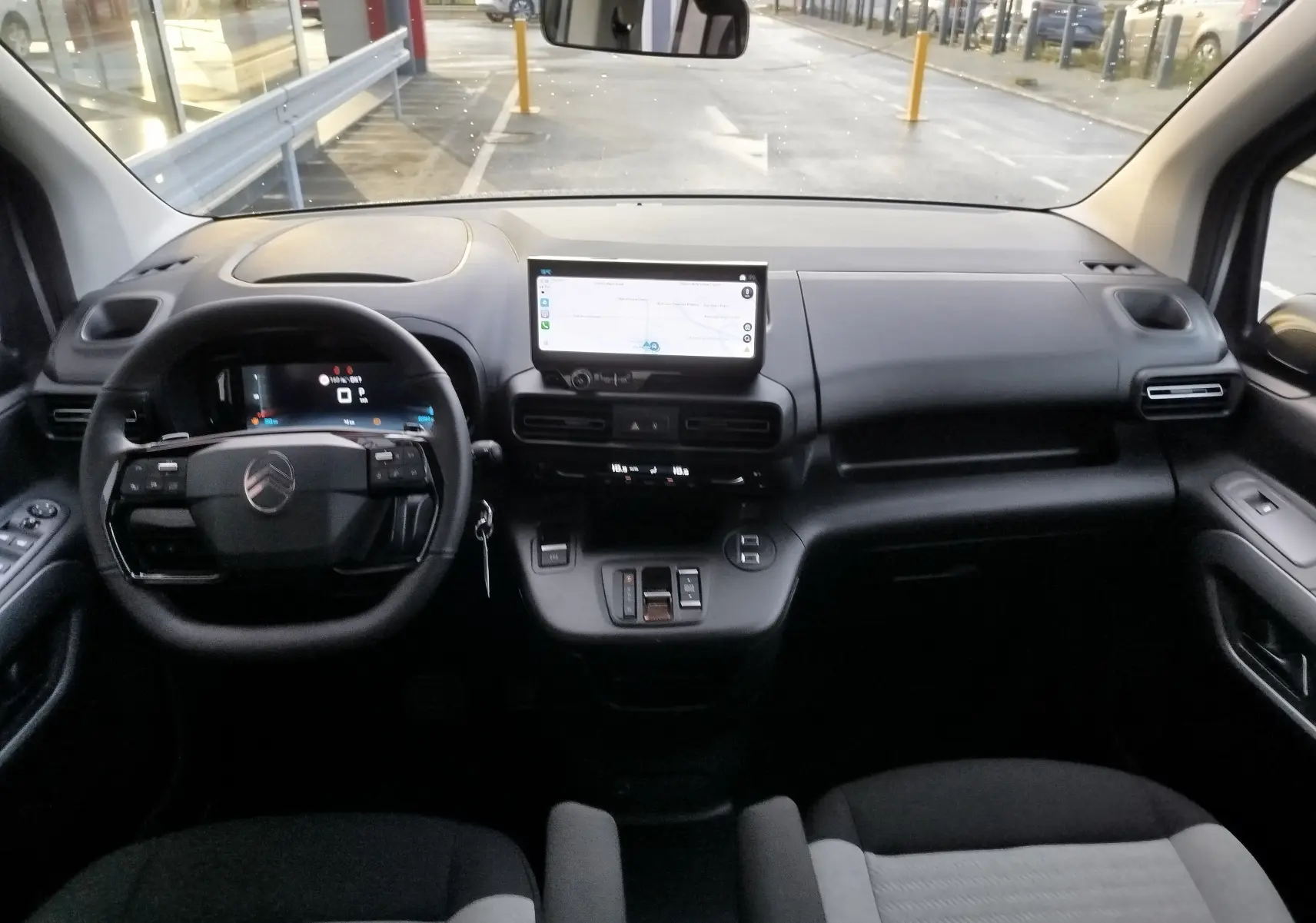 Vue intérieure avant du Citroën Berlingo gris acier 2026, avec tableau de bord numérique et écran tactile central.