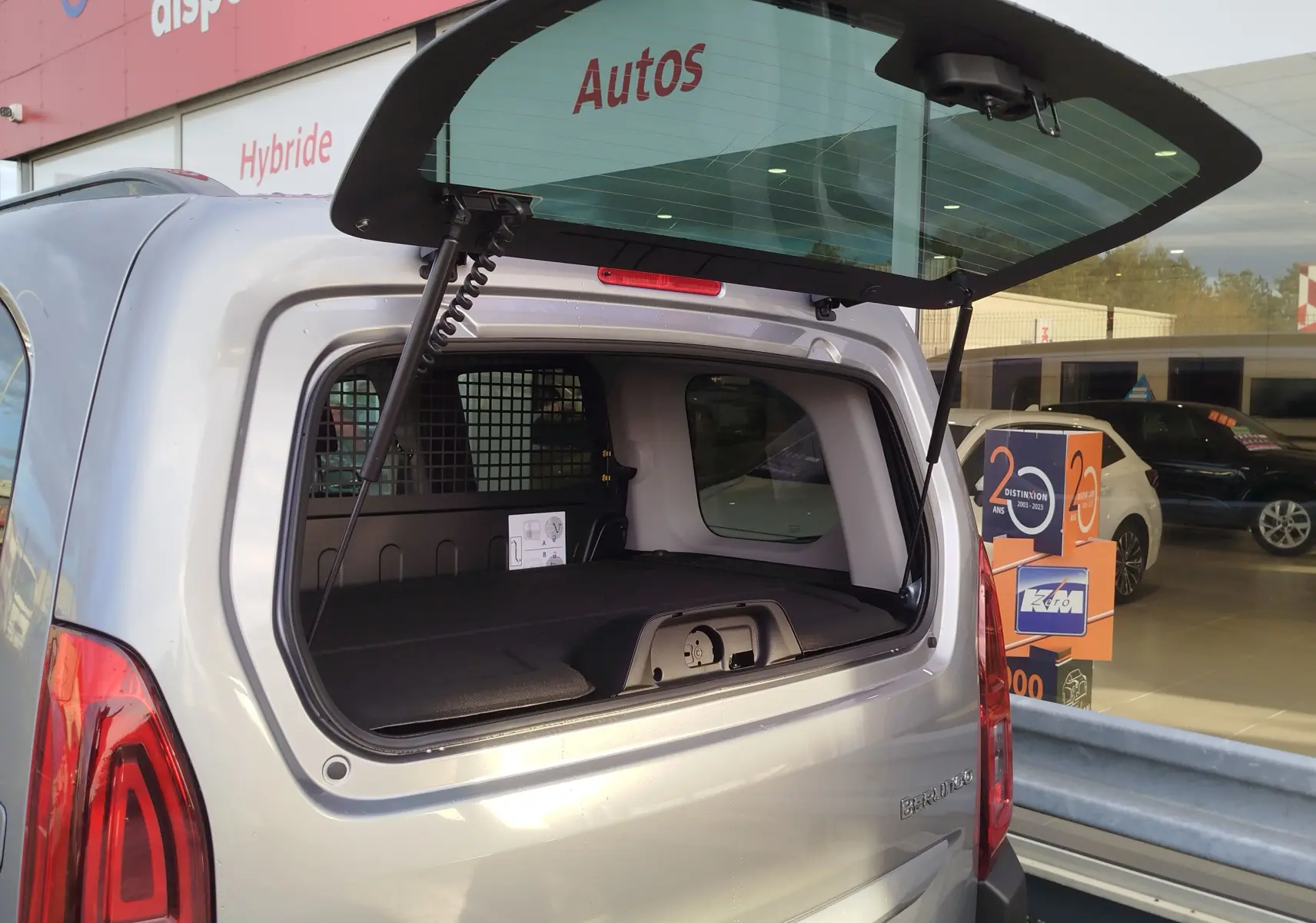 Vue arrière du Citroën Berlingo gris acier 2026 avec hayon ouvert, montrant l'espace de chargement utilitaire.