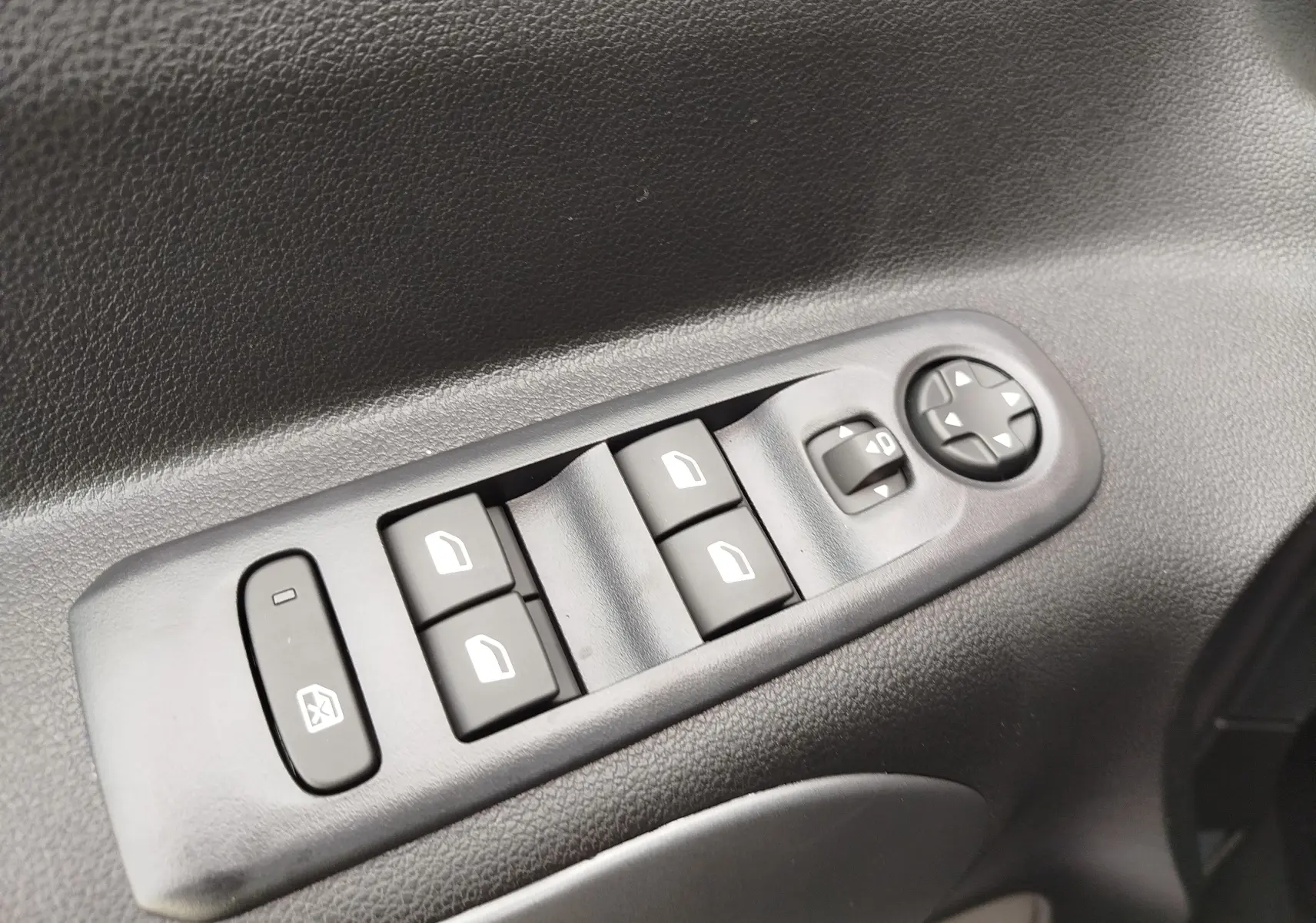 Gros plan sur les commandes de lève-vitres et réglage des rétroviseurs côté conducteur du Citroën Berlingo gris acier.