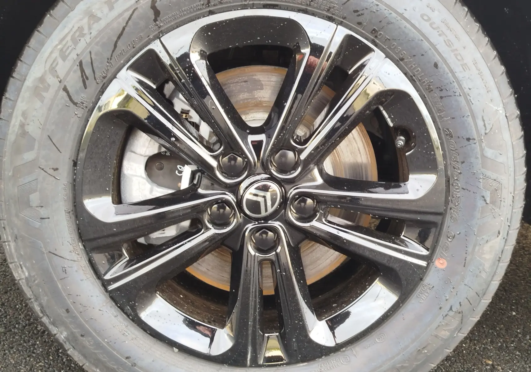 Gros plan sur la jante noire brillante avec logo Citroën au centre du Berlingo gris acier, roue avant droite visible.