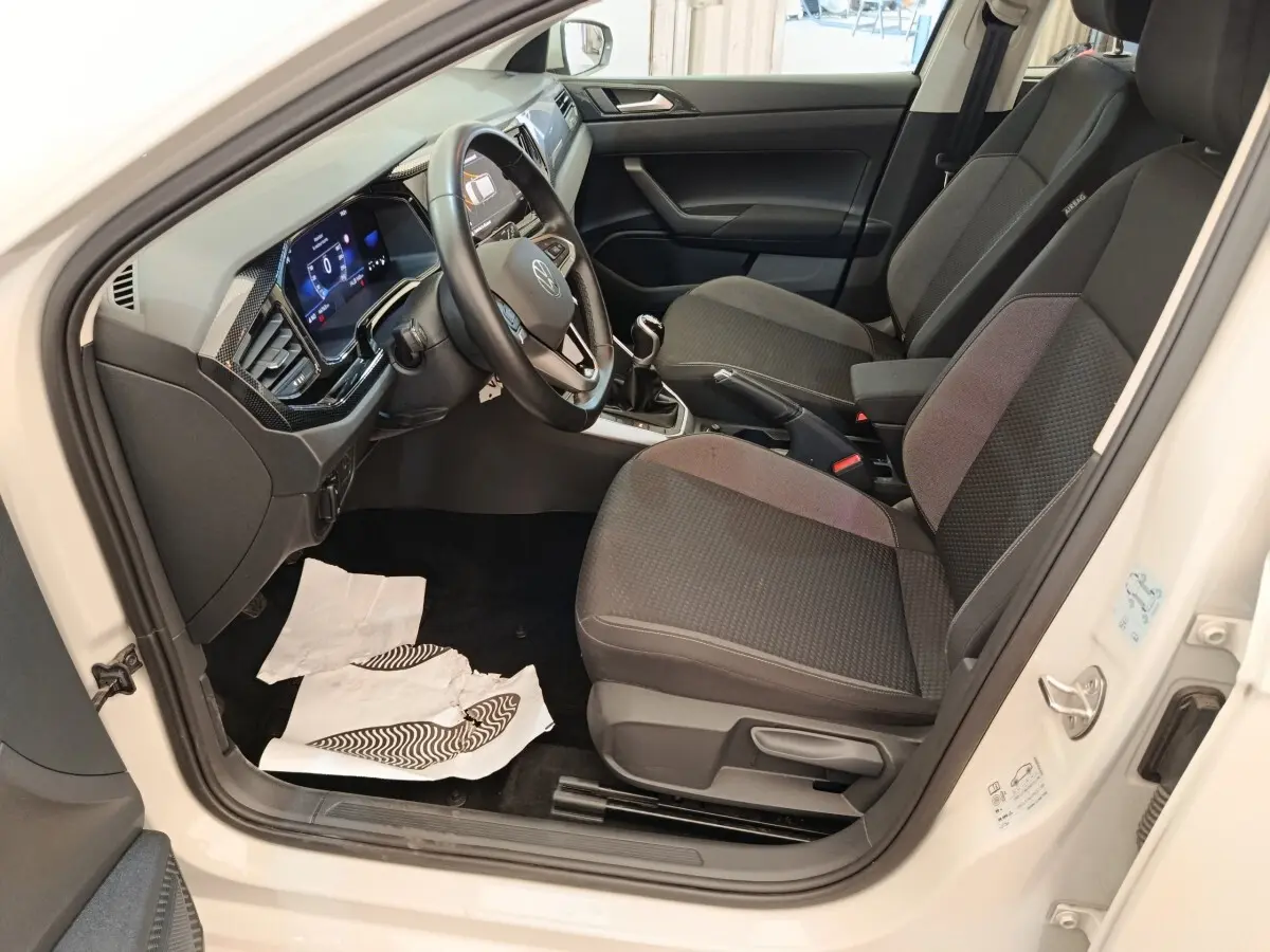 Vue intérieure côté conducteur de la Volkswagen Polo gris clair 2023, avec volant multifonctions et tableau de bord numérique.