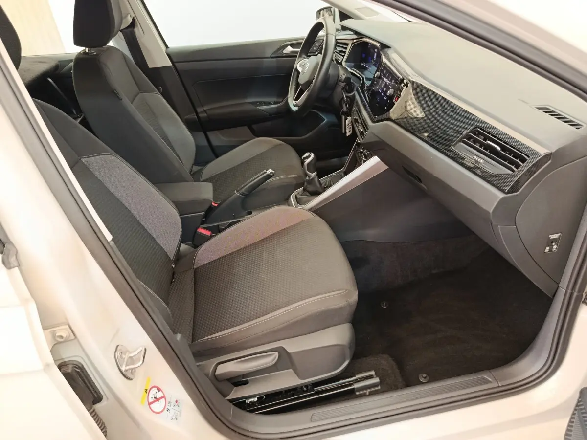 Intérieur avant droit de la Volkswagen Polo 2023, sièges gris foncé, volant multifonctions alu-cuir et tableau de bord digital.