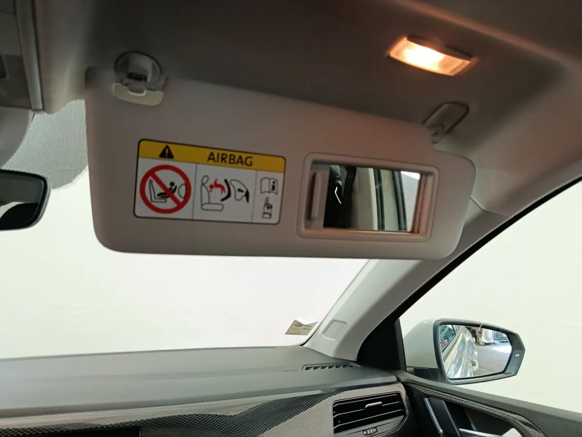 Vue intérieure côté passager du pare-soleil gris clair avec miroir et rétroviseur extérieur visible d’une Volkswagen Polo 2023.