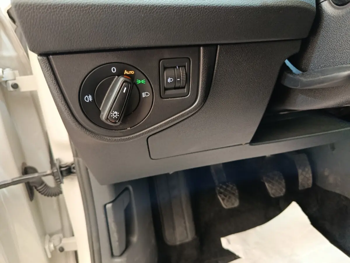 Vue rapprochée du tableau de bord côté gauche avec commande des phares et pédales d’une Volkswagen Polo gris clair 2023.