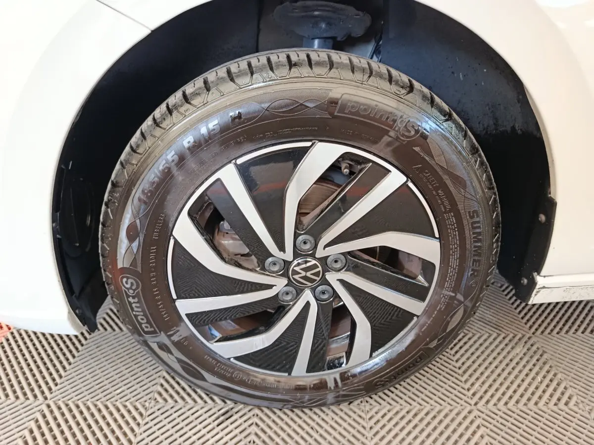 Gros plan sur la roue avant gauche d'une Volkswagen Polo gris clair avec jante alliage noir et argentée.