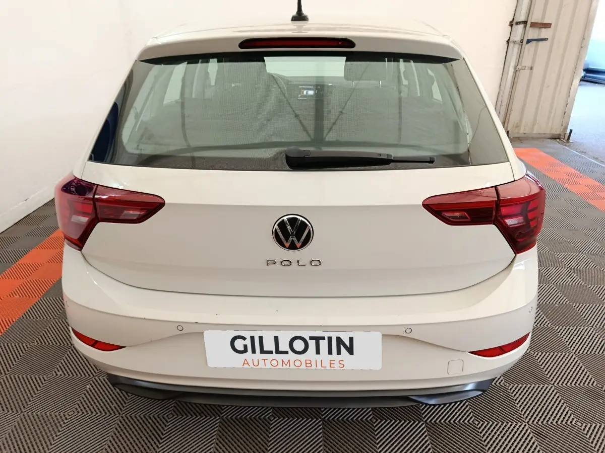 Vue arrière d'une Volkswagen Polo gris clair 2023 avec feux arrière rouges et logo VW centré.