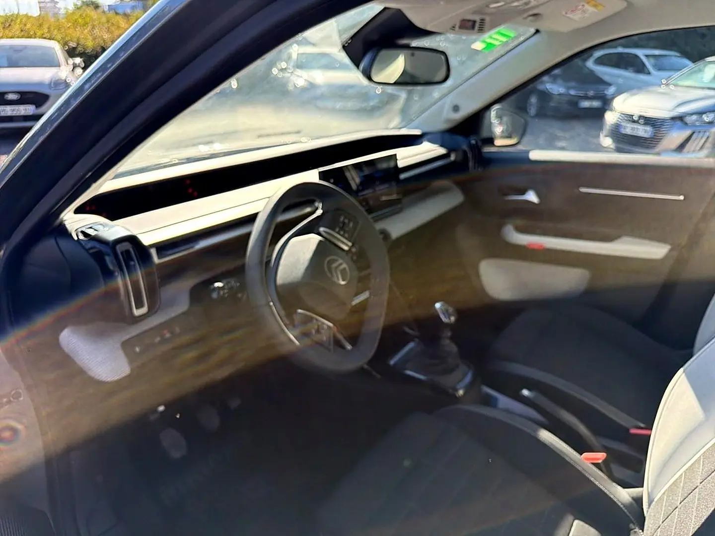 Vue intérieure côté conducteur de la Citroën C3 gris mercure, volant multifonction et levier de vitesses manuel visibles.